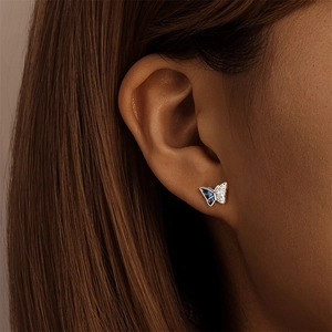 Vue détaillée d'une boucle d'oreille papillon asymétrique en argent avec émail bleu et cristaux