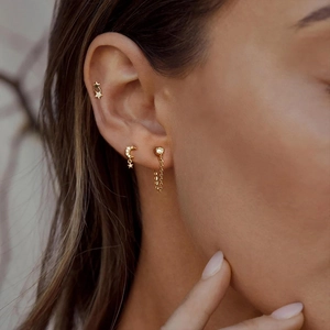 Detailed close-up of 925 silver four-petal flower and moon earring set on model