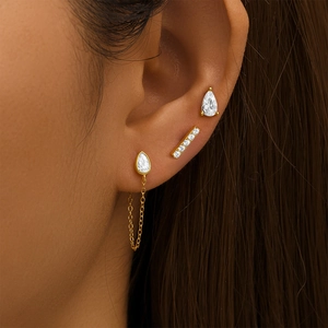 Close-up of golden S925 sterling silver three-piece earring set with zircons on ear