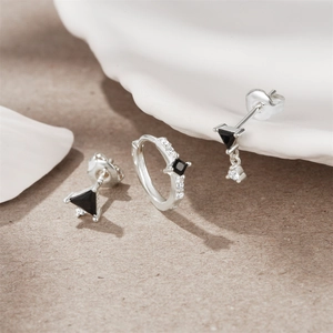 Macro shot of silver S925 geometric earrings set with black zircons on textured paper