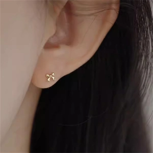 Nahaufnahme eleganter goldener Schleifenohrringe am Ohrläppchen mit glattem Design