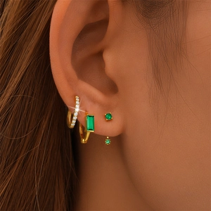 Close-up of S925 sterling silver emerald earrings set with gold finish on ear