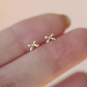 Nahaufnahme der 18k Gold Schmetterling Ohrstecker an einem Finger als Größenreferenz