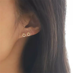 Nahaufnahme eleganter goldener Kronen-Ohrstecker mit Zirkonia, getragen am Ohrläppchen