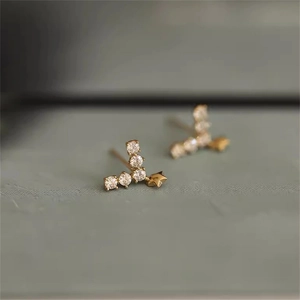 Nahaufnahme minimalistischer Gold-Meteor-Ohrstecker mit funkelnden weißen Zirkonia-Sternen