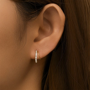 Detailed close-up of golden double hoop earrings with pave-set zircon stones on the model
