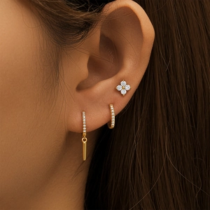 Detailaufnahme eines dreiteiligen goldenen Ohrring-Sets mit Zirkonia am Ohr des Models