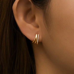 Detail of elegant gold double-row earrings featuring one smooth and one crystal-paved line