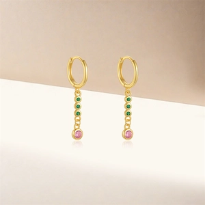 Detail of gold huggie hoop earrings with layered green and pink gemstones