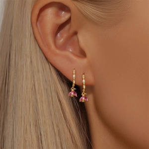 Close-up of gold hoop earrings with pink crystal flower drops on female model