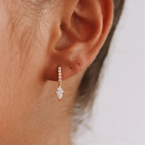Close-up of gold hoop earrings with marquise cut crystal and pave zircon setting