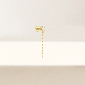 Détail d'un piercing labret en argent S925 doré avec zircon rond et fine chaîne pendante