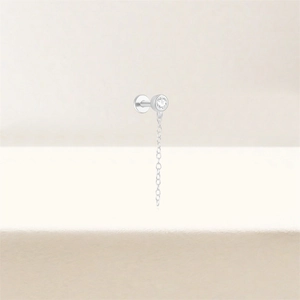 Détail macro du piercing labret en argent S925 avec zircon et une fine chaîne métallique