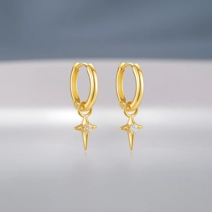 Macro shot of gold hoop earrings with star pendants and sparkling center zircon stones