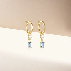 Close-up of S925 sterling silver gold earrings with blue and white zircon star drops