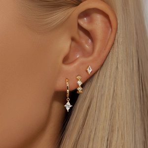 Close-up of a 3-piece gold S925 silver earring set with crystals on a model's ear