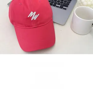 Close-up of pink baseball cap featuring white MW letter embroidery and cotton twill fabric