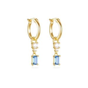 Detail of gold hoops featuring sparkling white zircon and rectangle sky blue gemstones