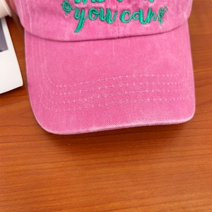 Detailed macro view of embroidered 'you can' lettering on vintage washed pink cotton cap
