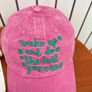 Detail of rose pink washed cotton baseball cap with green embroidered inspirational text