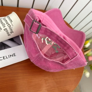 Close-up of washed pink cotton baseball cap with adjustable metal buckle and green embroidery