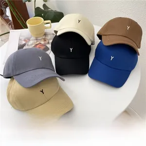 Close-up of six assorted cotton baseball caps with small Y embroidery on a table