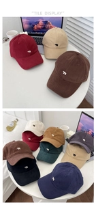Détail montrant divers coloris de casquettes en coton avec broderie ours empilées