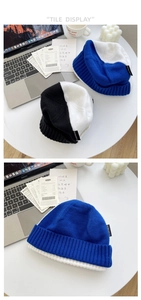 Texture détaillée du bonnet en maille bicolore bleu et blanc avec écusson logo