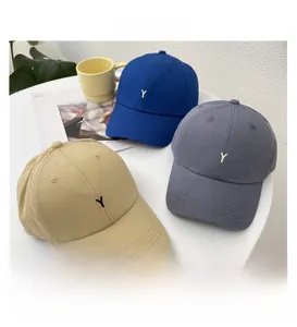 Detailed flat lay of cotton baseball caps in blue, grey, and khaki with Y embroidery