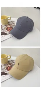 Detailed view of gray-blue and khaki cotton baseball caps with embroidered Y letter