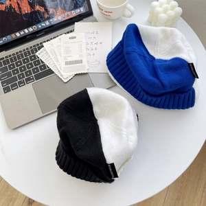 Bonnet en tricot bleu et blanc avec étiquette noire posé sur table avec accessoires