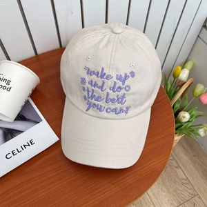 Detail of off-white cotton baseball cap with purple motivational text and floral embroidery