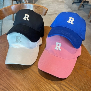 Gorras de béisbol clásicas en negro azul blanco y rosa con logo R sobre mesa de madera