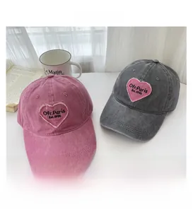 Detail of pink heart embroidery with Ofr. Paris text on washed cotton baseball caps