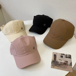 Waterproof ponytail baseball caps in four colors with KT metal logo on a white table