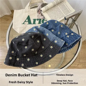 Detail of embroidered daisy patterns on black and blue denim bucket hats for sun protection