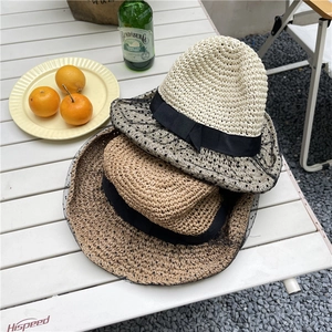 Straw sun hat with black polka dot mesh brim for women in a leisure outdoor setting