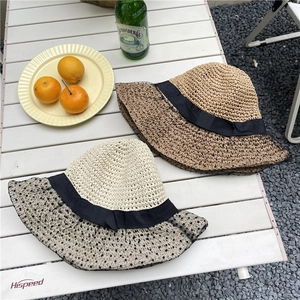 Straw sun hats with black polka dot mesh veil and ribbon bows on an outdoor table