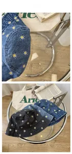 Detail of daisy flower embroidery on denim bucket hats in black and blue colors