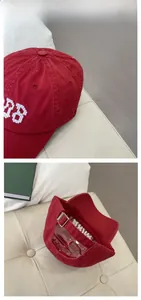 Detail of red vintage cotton baseball cap showing white embroidery and metal buckle