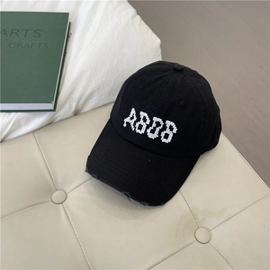 Black cotton baseball cap with pixelated letter embroidery and distressed brim details