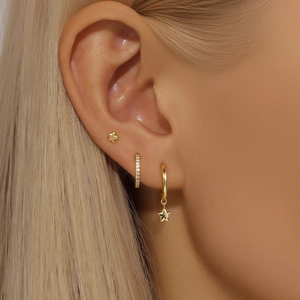 Gros plan de boucles d'oreilles étoiles dorées et créoles en zircon sur un mannequin
