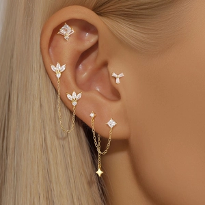 Detail view of gold S925 silver clover earrings with zircon studs on ear cartilage