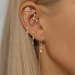 Macro shot of gold lotus helix earrings with white zircon crystals on a model's ear