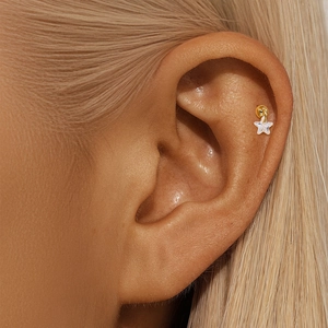 Detail view of a 925 silver lotus stud earring with star pendant on ear cartilage