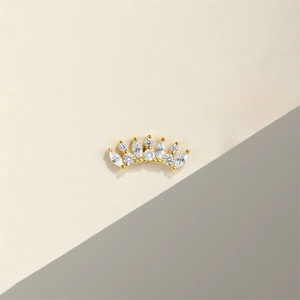 Macro shot of gold crown earrings with sparkling zircon gemstones on a minimal background