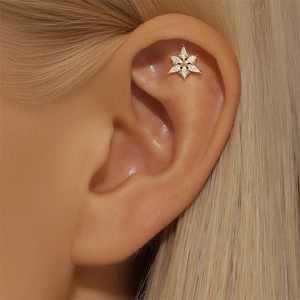 Macro view of a gold snowflake ear stud with marquise-cut zirconias on ear cartilage
