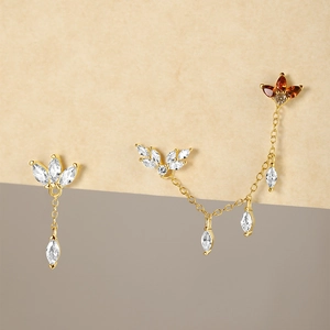 Detailed view of gold leaf stud earrings with amber and white marquise-cut zircon stones