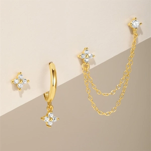 Detalle de pendientes florales dorados con circonitas brillantes y flecos de cadena