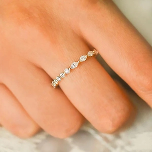 Macro view of gold eternity ring with marquise cut diamonds and elegant lace backdrop